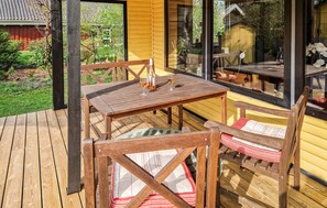 A wooden deck with a table and chairs, a bottle of wine, and glasses on the table.