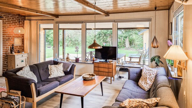 A spacious living area with a wooden ceiling, large windows, a television, and a dining table. - 2 bedroom awesome home in Tarm (Tarm)