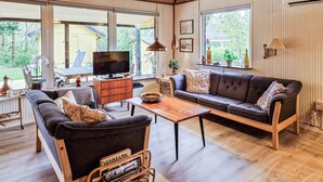 A cozy living room with a sofa, a coffee table, a TV, and a wooden cabinet. - 2 bedroom awesome home in Tarm (Tarm)