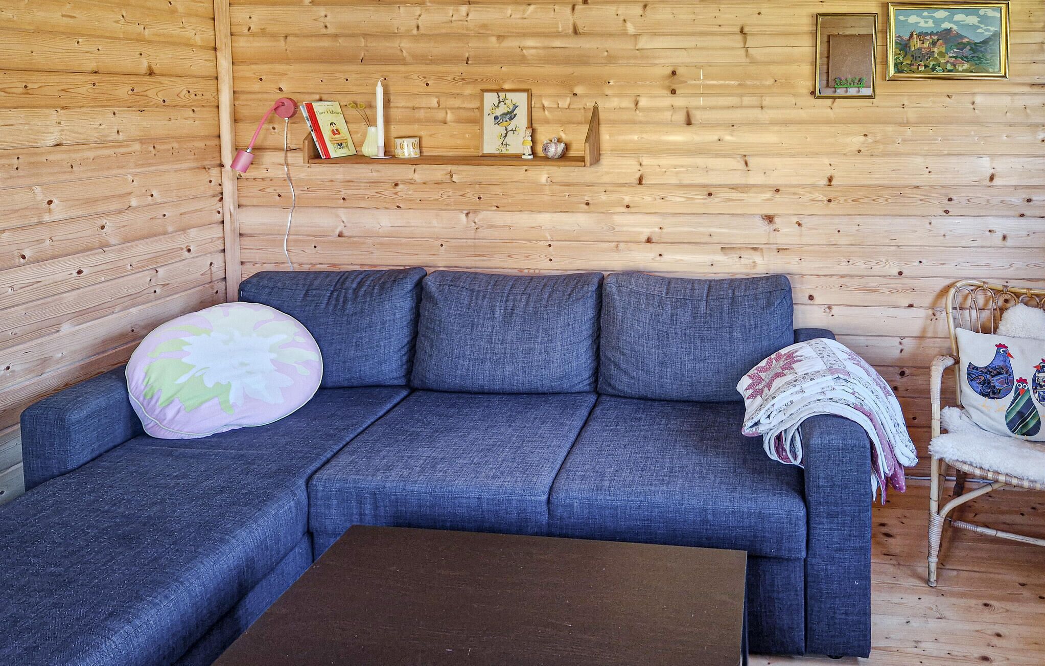 A cozy room with a blue sofa, a small wooden table, and a wicker chair.