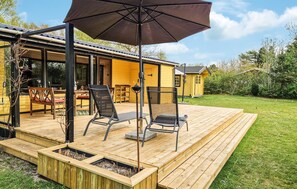 Une terrasse en bois avec des siĂšges dâextĂ©rieur, une pergola et un petit bĂątiment.