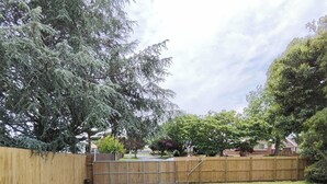 A backyard with a wooden fence, a paved path, and a grassy area. - 3-Bedroom House +Private yard+sliding gate (Hamilton)
