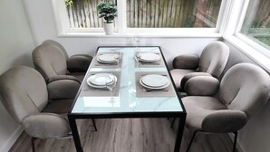 A dining table with four chairs, a glass top, and a window view. - 3-Bedroom House +Private yard+sliding gate (Hamilton)