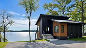 A modern two-story house with a balcony, a driveway, and a lake view. - Waterfront Luxury - Hot Tub, Game Room, Kayaks, Best View (Cadiz)