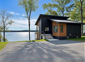 A modern two-story house with a balcony, a driveway, and a lake view.
