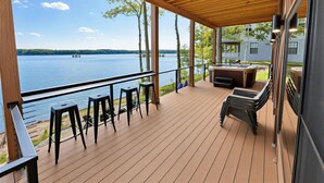 A wooden deck with a hot tub, bar stools, and a view of a lake. - Waterfront Luxury - Hot Tub, Game Room, Kayaks, Best View (Cadiz)