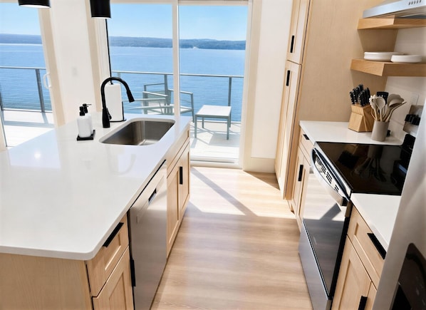 A modern kitchen with a large island, a built-in oven, and a view of the water.
