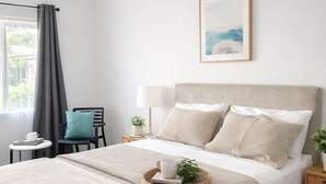 A neatly arranged bedroom with a large bed, a bedside table, a chair, and a window with curtains. - Banksia Motel Bass Hill (Bass Hill)