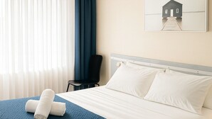 A hotel room with a bed, a chair, a window with curtains, and a painting on the wall. - Banksia Motel Bass Hill (Bass Hill)