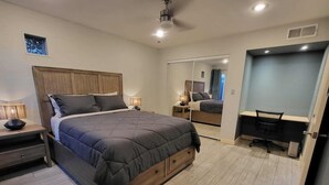 Quarto moderno com uma cama grande, mesas de cabeceira, escrivaninha e um espelho.