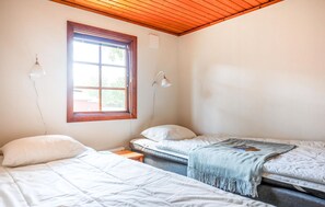 A bedroom with two beds, a window, and two wall-mounted lamps.