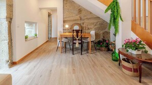 A dining area with a wooden table and chairs, a stone wall, and a staircase. - Rustic & Modern Stone House by Host Wise (Pedroso)