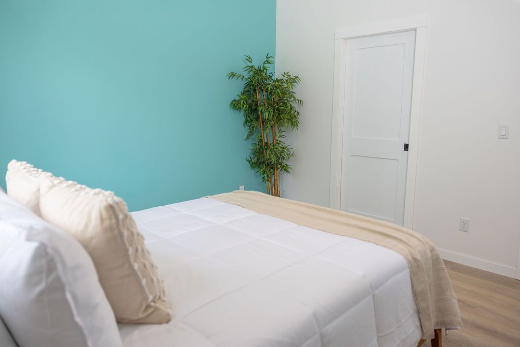 A bedroom with a bed, a plant, and a door.