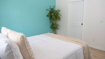 A bedroom with a bed, a plant, and a door.