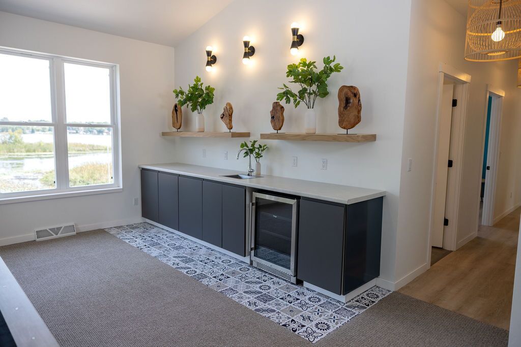Een moderne keuken met donkere kastjes, een centraal eiland en decoratieve planten op zwevende planken.