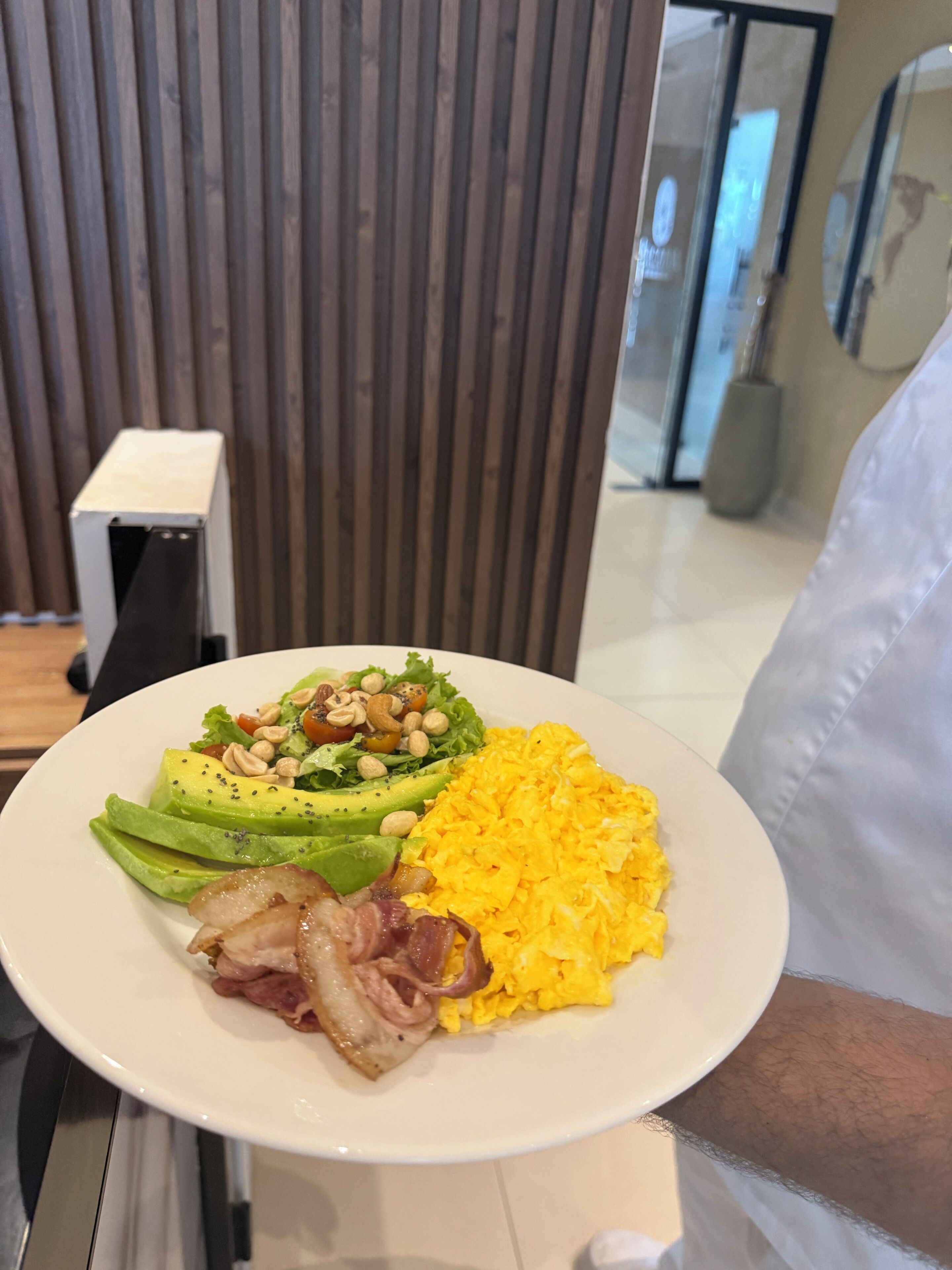 A plate of food with avocado, nuts, and scrambled eggs.