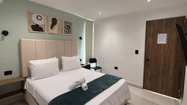 Una habitación de hotel con una cama, un escritorio y una puerta.