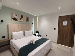 Une chambre d’hôtel avec un lit, un bureau et une porte.