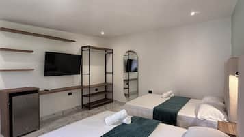 Ein Hotelzimmer mit zwei Betten, einem Schreibtisch, einem Fernseher und einem Spiegel.
