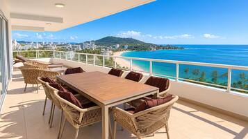 A balcony with a view of a beach and cityscape.