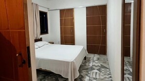 A bedroom with a bed, a ceiling fan, a wardrobe, and a mirror. - Casinhas da Toca 1 - Quiet house 30 minutes from the main tourist attractions. (Armação dos Búzios)