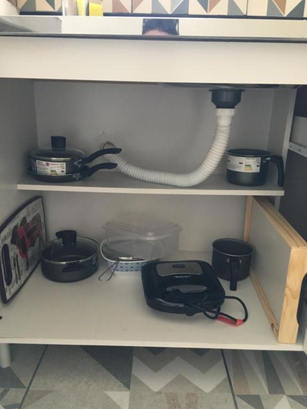 Une cuisine dotée d’un plan de travail blanc, d’une hotte blanche et de divers appareils de cuisine, notamment un cuiseur à riz, une bouilloire et une machine à café.