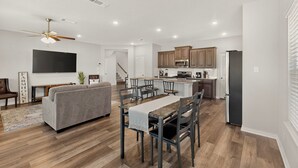A modern kitchen with wooden cabinets, a built-in microwave, and a stainless steel refrigerator. - Modern Home on the Texas Prairie (Gainesville)