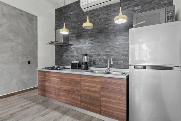 A modern kitchen with a built-in microwave, stainless steel refrigerator, and a double sink.
