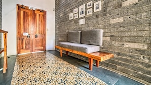 A room with a wooden door, a bench, a grey sofa, and a patterned rug. - Beautiful Room Villa San Juan (Nuevo Vallarta)