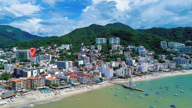 Eine Küstenstadt mit dichter Bebauung, einem Strand und einer Bergkulisse im Hintergrund.