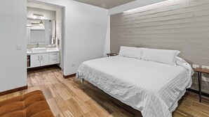 Ein Schlafzimmer mit Bett, Nachttisch, Holzboden und Deckenventilator.