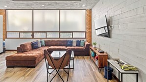 Ein modernes Wohnzimmer mit einer Eckcouch, einem Schlafsofa, einem flachbildfernseher an der Wand und einem Holztisch.