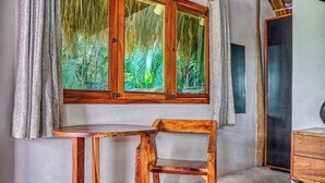 Een kamer met een houten tafel en stoel, een raam met gordijnen en een houten kast.