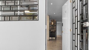 Un pasillo con una cocina moderna al fondo, que presenta un salpicadero de ladrillo y electrodomésticos contemporáneos.