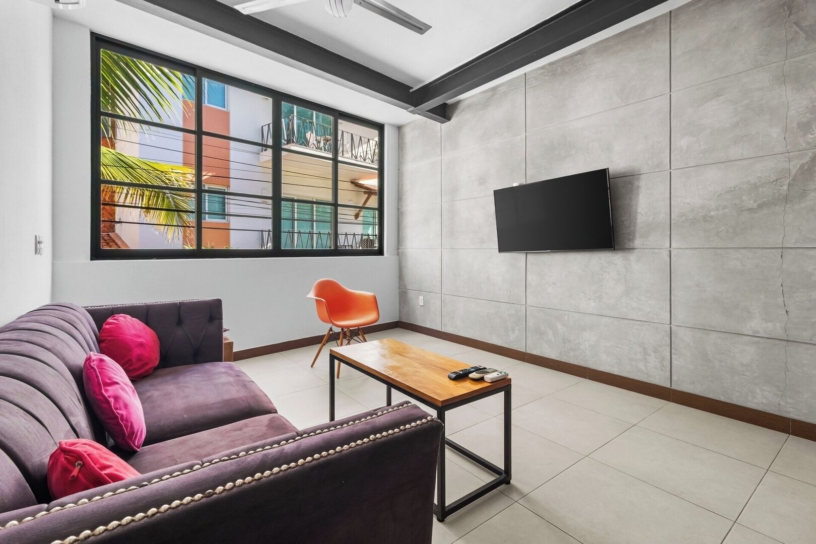 A modern living room with a sofa, a coffee table, and a TV mounted on the wall.
