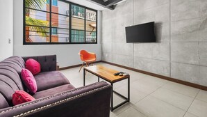 Een moderne woonkamer met een bank, een salontafel en een aan de muur bevestigde televisie.