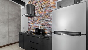 Een keuken met een moderne, roestvrijstalen koelkast, een gasfornuis en een kleurrijke backsplash van baksteen.