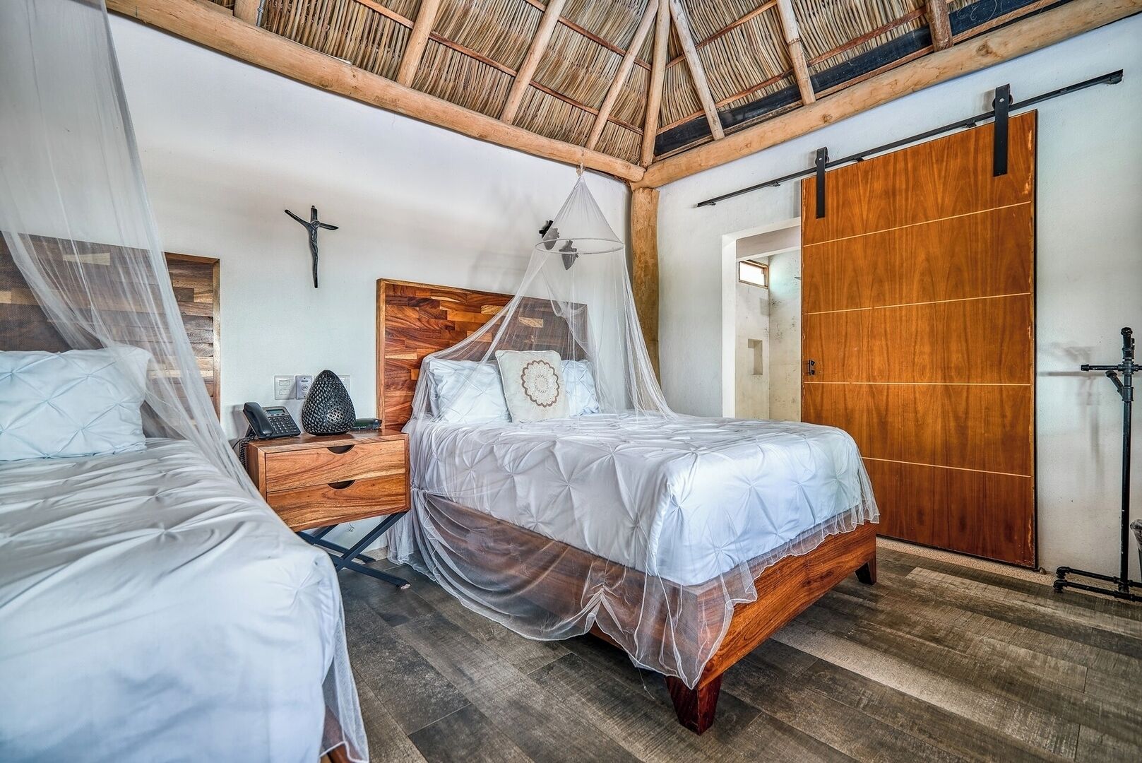 Ein Schlafzimmer mit zwei Betten, einem Holzschrank, einem Nachttisch und einem Moskitonetz.
