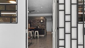 An interior view of a modern kitchen with a brick backsplash, a central island with stools, and a ceiling fan. - Simple loft in a romantic area + Wi-Fi + beach (Puerto Vallarta)