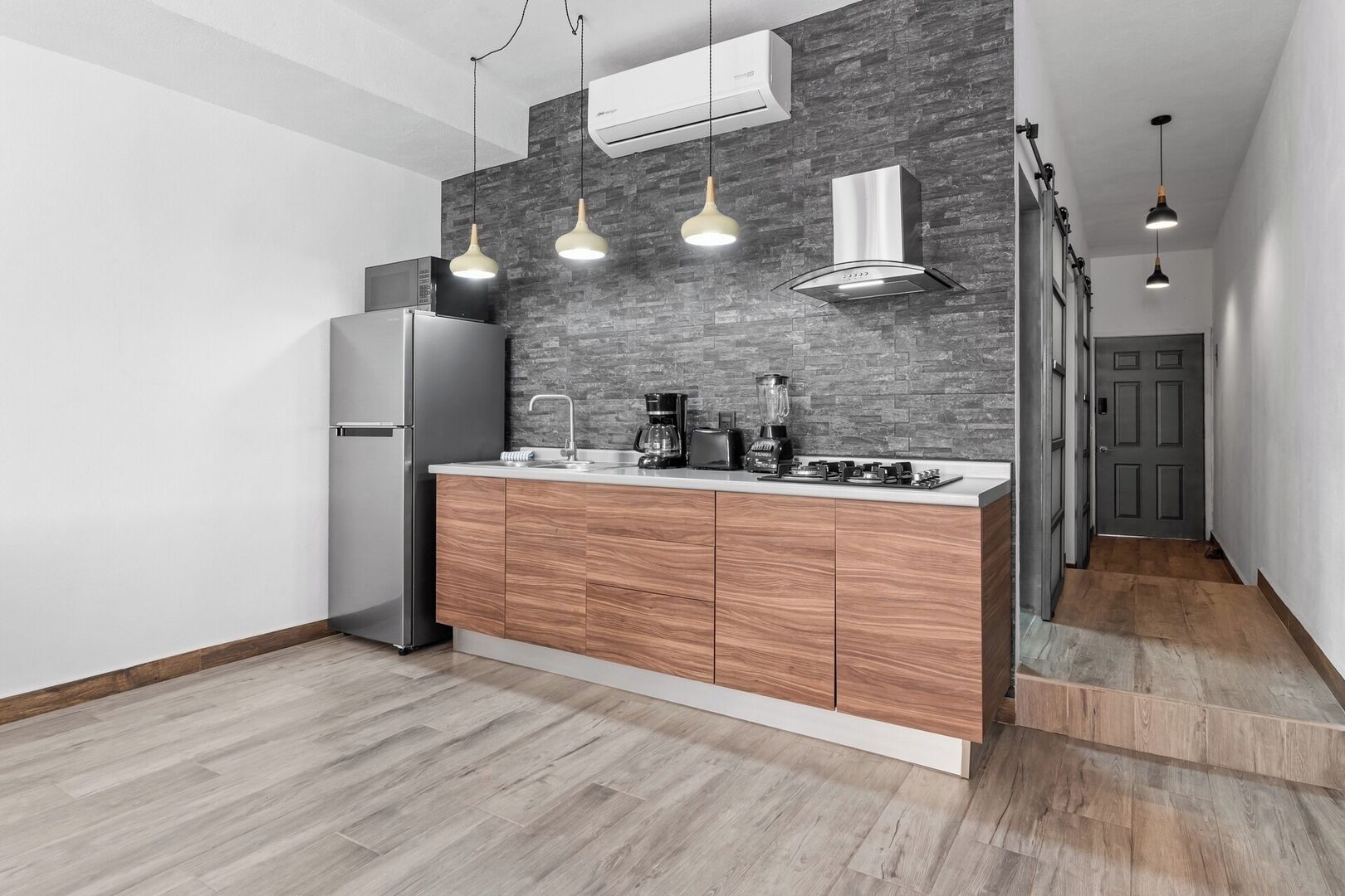 Una cocina moderna con encimera de madera, electrodomésticos de acero inoxidable y un salpicadero de ladrillo gris.