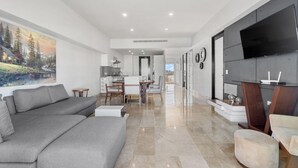 Un salon moderne avec un canapé gris, un coin repas et une cuisine en arrière-plan.