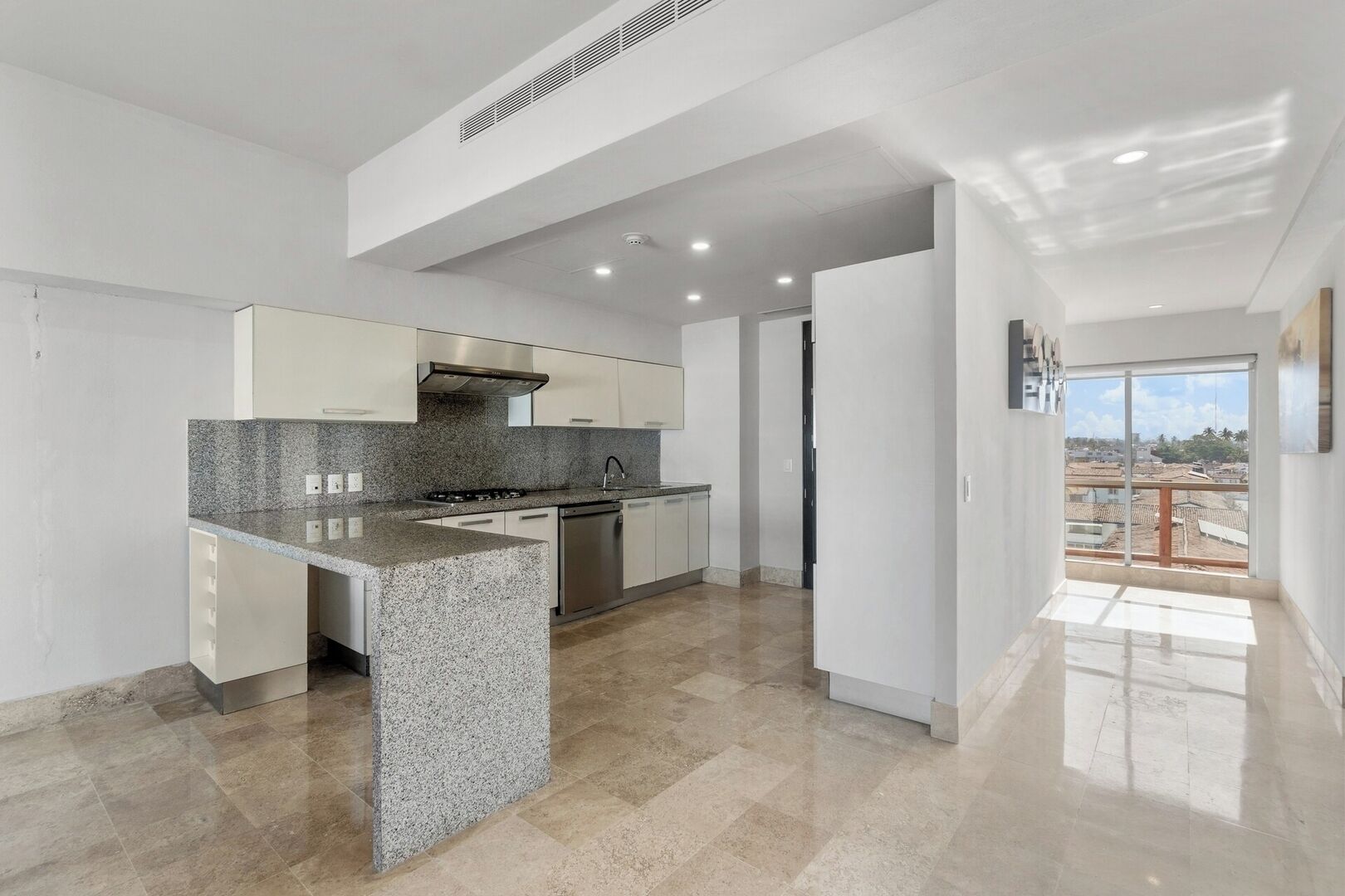 A modern kitchen with granite countertops, stainless steel appliances, and a view of the city through a large window.