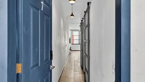 A hallway with a blue door marked with the number 7, leading to a room with a large window. - Prime location in the Romantic Zone + beach (Puerto Vallarta)