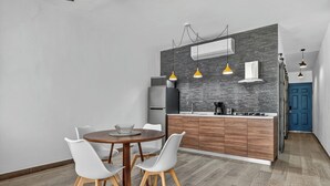 A modern kitchen with a central island, white chairs, and a round dining table. - Prime location in the Romantic Zone + beach (Puerto Vallarta)