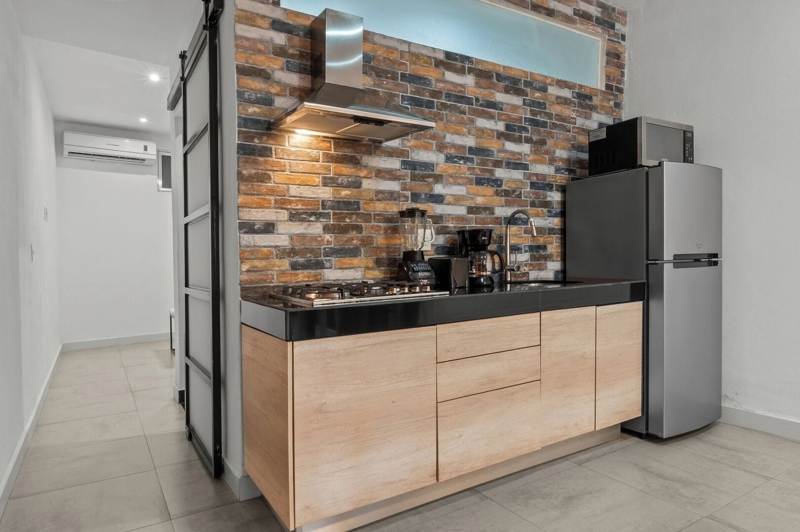 A modern kitchen with a brick backsplash, stainless steel appliances, and a wooden countertop.