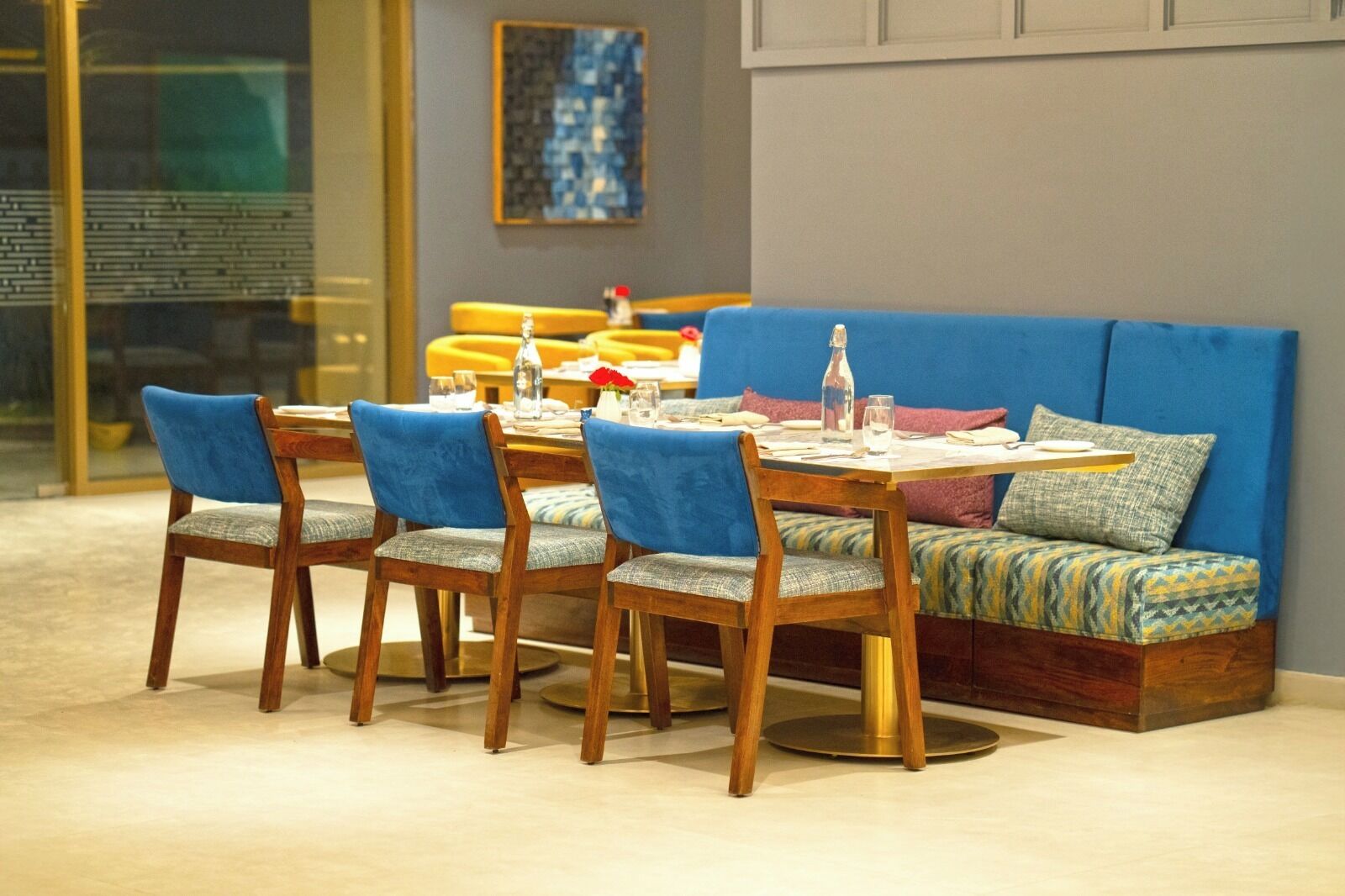 A dining area with a wooden table, blue upholstered chairs, and a blue sofa with patterned cushions.