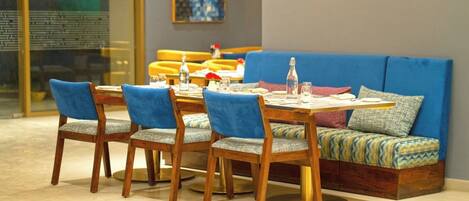 A dining area with a wooden table, blue upholstered chairs, and a blue sofa with patterned cushions.