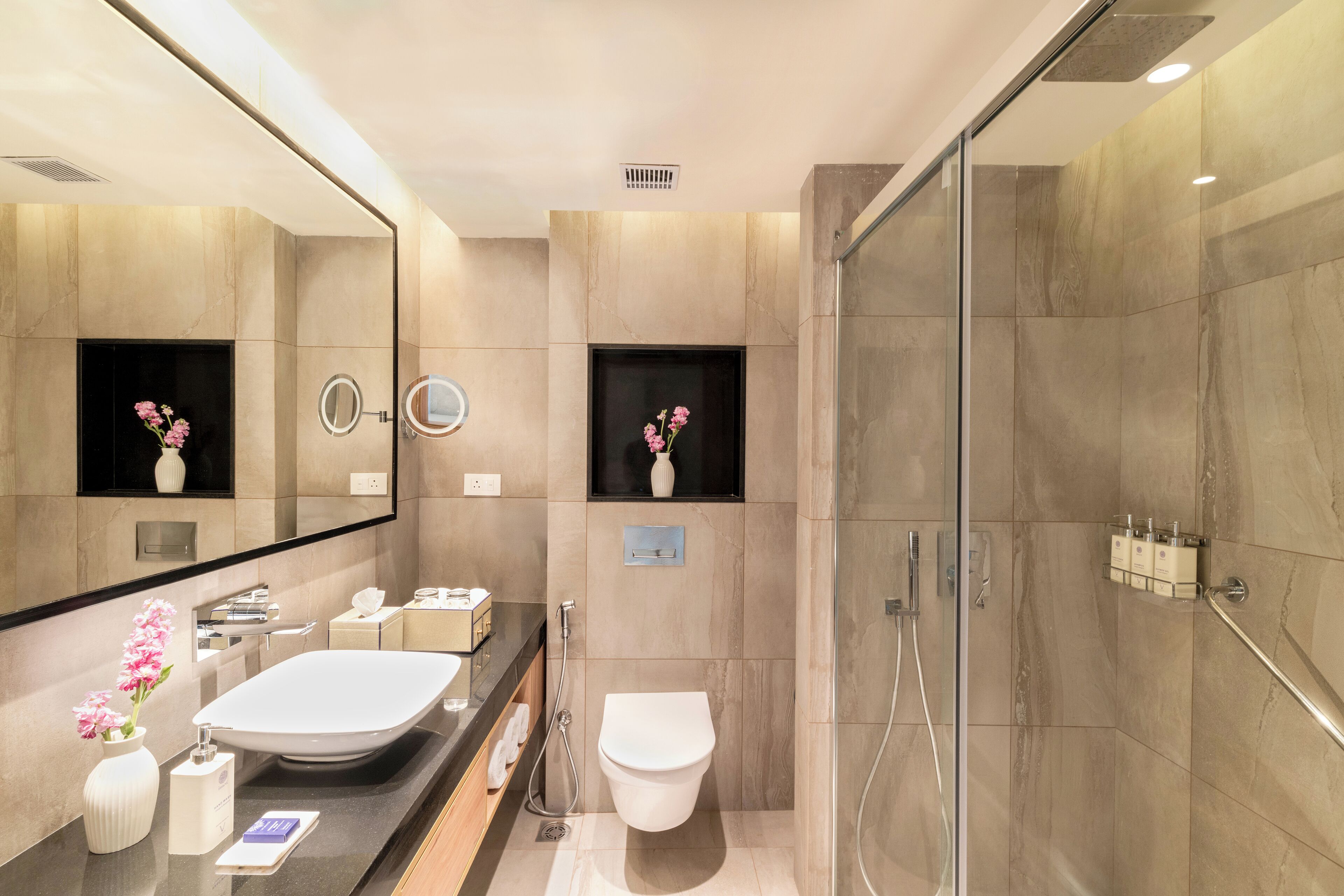 Un baño moderno con un espejo grande, un lavabo blanco, un inodoro y una zona de ducha.