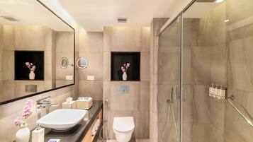 Un baño moderno con un espejo grande, un lavabo blanco, un inodoro y una zona de ducha.