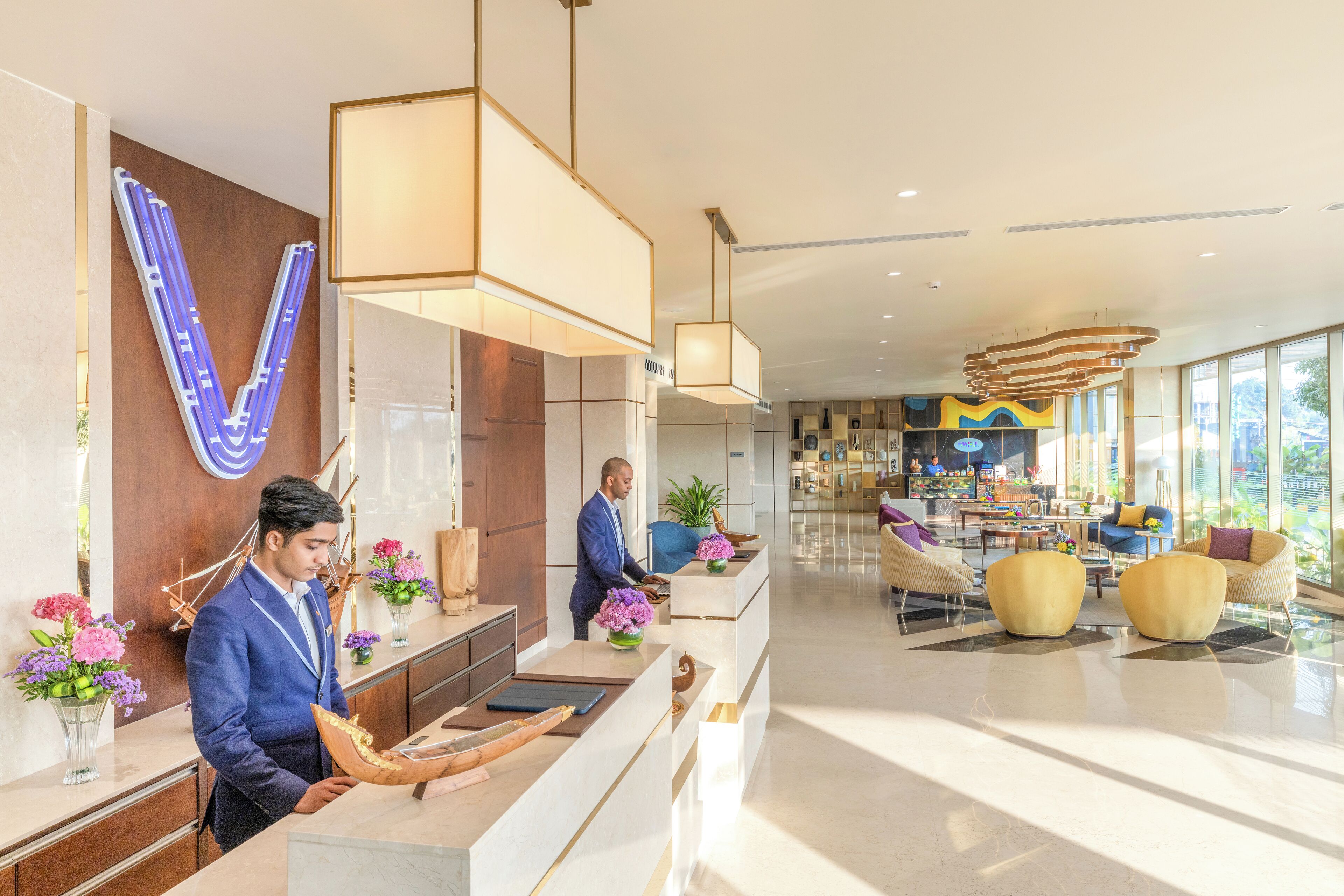 Zona de recepción de hotel con diseño moderno, una mesa de recepción y un área de estar con sofás y una mesa de centro.